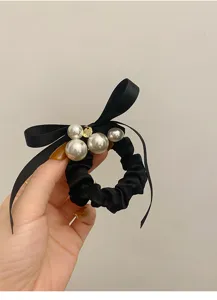 Zwarte satijnen haarelastiek in Franse stijl met strik, elegante parels en gouden bedeltje.