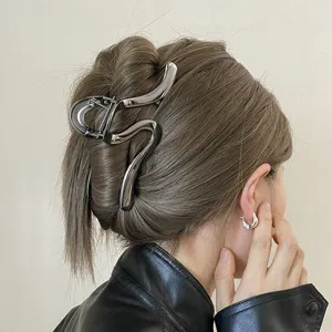 Detail shot of a minimalist metal hair claw clip, abstract linear design for thick hair updo.