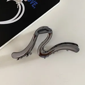 Detail shot of the minimalist metal hair claw clip, featuring a unique abstract line design for thick hair.