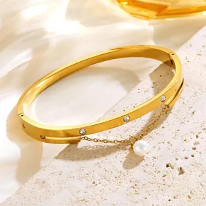 Gold titanium steel cuff bracelet detailed with shimmering crystals and a delicate pearl pendant.