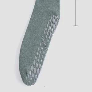 Nahaufnahme grüner Yoga Grip Socken mit rutschfesten Silikonpunkten für sicheres Pilates Training.