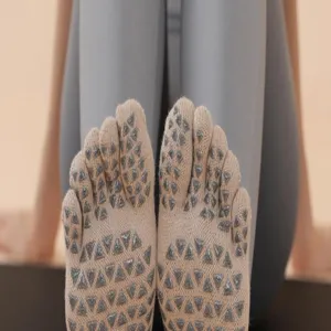 Close-up of beige five-toe yoga socks with grey silicone grip dots for pilates and fitness.