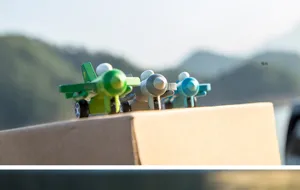 Detailed shot of cute mini wooden toy airplanes in green, grey, and blue colors outdoors.