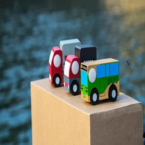 Wooden toy vehicle detail showing colorful wooden cars and a bus model placed on a box.