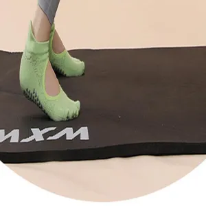 Detail view of green five-toe grip yoga socks on mat, showing non-slip dots and breathable fit.