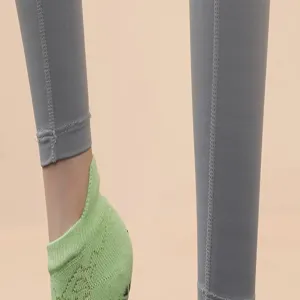 Detail shot of women's anti-slip yoga sports socks and grey leggings, comfortable material.