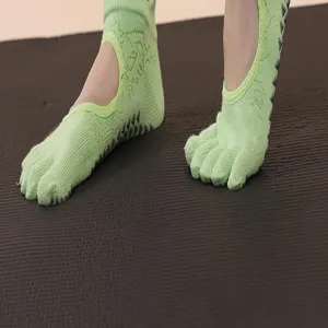 Detail view of light green five toe yoga socks with grip dots for pilates and fitness.