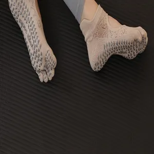 Beige five-toe yoga socks with anti-slip grip dots for Pilates and fitness workouts.