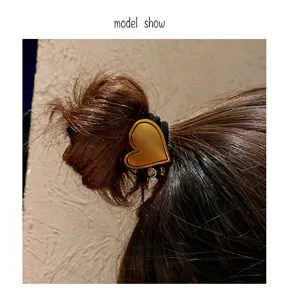 Close-up detail shot of the elegant gold heart hair tie worn on a stylish hair bun.