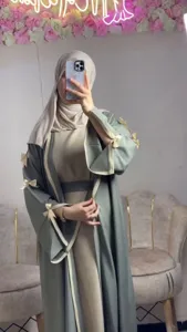 Detail view of sage green open-front abaya robe featuring elegant decorative bows on sleeves.