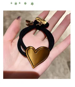 Detailed view of Korean style black hair rope with gold heart charm for women ponytail styling.