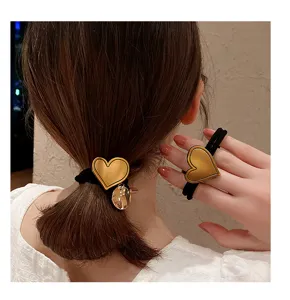 Stylish gold heart hair tie, black elastic ponytail holder, chic fashion hair accessory detail.
