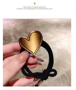 Detail view of a stylish black hair tie featuring a chic golden heart charm and metal ends.