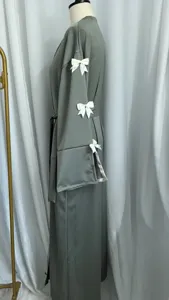 Close-up detail of the grey long robe showing delicate white bow accents on the sleeve.