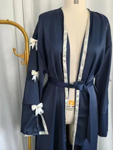 Dark blue satin robe detail featuring elegant white bows and contrast piping along the front.