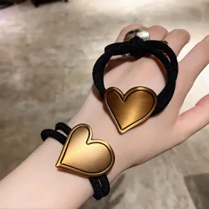 Black elastic hair tie with bronze heart metal ornament, chic ponytail holder for women.