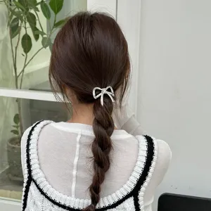 Vista dettagliata di un elastico per capelli con fiocco metallico argentato e treccia.