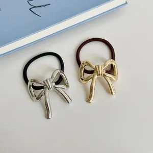 Primo piano dettagliato di eleganti elastici per capelli con fiocco in metallo argento e oro.