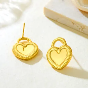 Close-up detail of golden heart padlock studs with radiant textured rims on white surface.