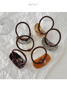Detail view of stylish geometric acetate hair ties with brown elastic bands, multi colors.