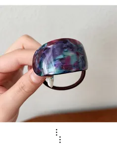 Resin curved hair tie detail showing unique blue and purple marbled pattern with elastic.