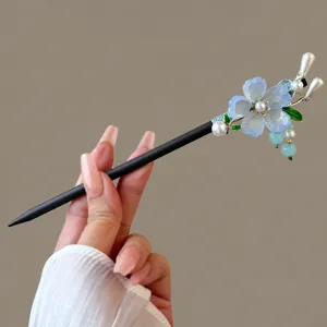 Nahaufnahme des traditionellen chinesischen Holzhaarstaebchens mit blauen Blumen und Perlen.
