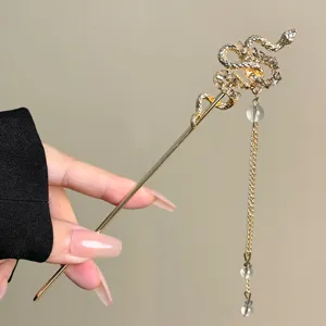 Gros plan du bâton de cheveux serpent doré vintage avec strass et pampille de perles.
