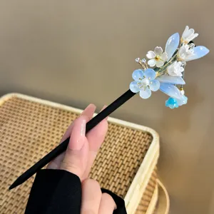 Gedetailleerd beeld van de Chinese haarspeld met blauwe bloemen en zwarte houten steel.