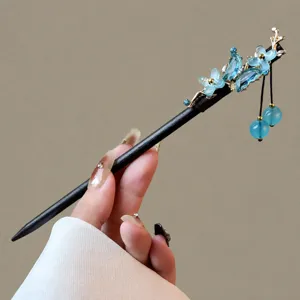 Detailed close-up of the vintage Chinese wooden hairpin featuring blue crystal flower and tassel.