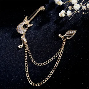 Detailed shot of gold-tone guitar brooch with sparkling rhinestones and delicate chain fringe.