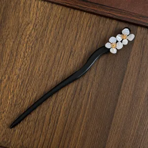 Close-up detail of Chinese style wooden hairpin with elegant white shell flower decoration.