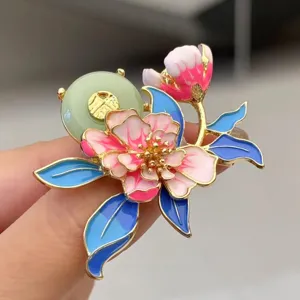 Detailed shot of exquisite Chinese style enamel peony brooch with jade ring, elegant accessory.
