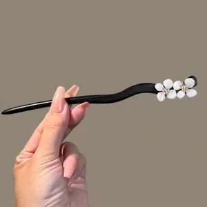 Close-up detail showing the exquisite black wooden hair stick with beautiful floral decor.