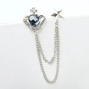 Close-up detail of silver crown heart crystal brooch with double chains and star pendant.