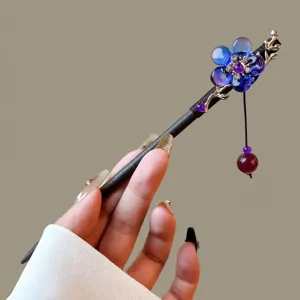 Detail view of Chinese vintage wooden hairpin with blue floral resin charm and dangling bead.