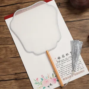 Detailed shot of traditional Chinese white silk round fan with wooden handle and silver tassel.