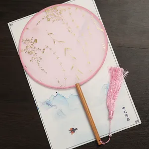 Éventail rond chinois traditionnel avec motif doré, manche en bois et pompon rose.