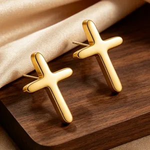 Nahaufnahme Detail minimalistischer glatter Edelstahl Kreuz Ohrstecker, gold glänzend.