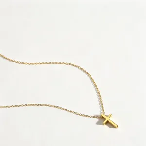 Detailaufnahme einer goldenen Kreuz-Halskette mit filigraner Kette auf weissem Grund.
