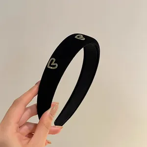 Elegant black velvet headband featuring sparkling rhinestone heart details for women.