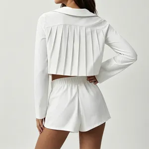 Ensemble crop top à manches longues plissé blanc et short taille haute pour le tennis.
