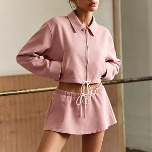 Pink zip up cropped jacket and low waist skirt detail view, casual athletic set.