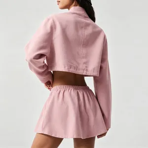 Detailed back view of a pink women's cropped athletic zip jacket and pleated tennis skirt set.