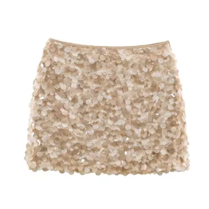 Close-up detail of the sparkling sequin mini skirt surface, showcasing dense champagne paillettes.