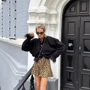 Women black knit cardigan jacket with feather cuffs and leopard print mini skirt outfit.