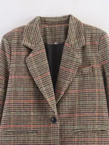 Close-up detail of women's vintage plaid tweed blazer collar and button design texture.