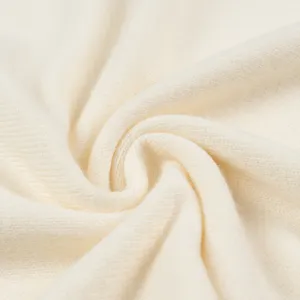 Nahaufnahme von weichem cremefarbenem Strickstoff mit feiner Textur und fließender Qualität.