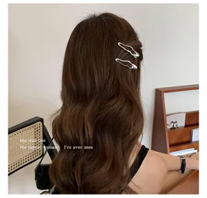 Vista detallada de pinzas para el cabello de metal plateado, elegante accesorio femenino.