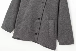 Détail de veste en mélange de laine grise montrant texture, revers, boutons et poches.