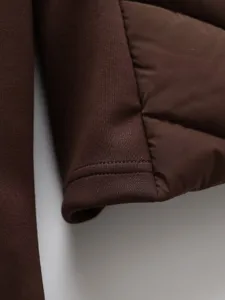 Dark brown puffer jacket sleeve cuff detail and stylish quilted fabric close-up display